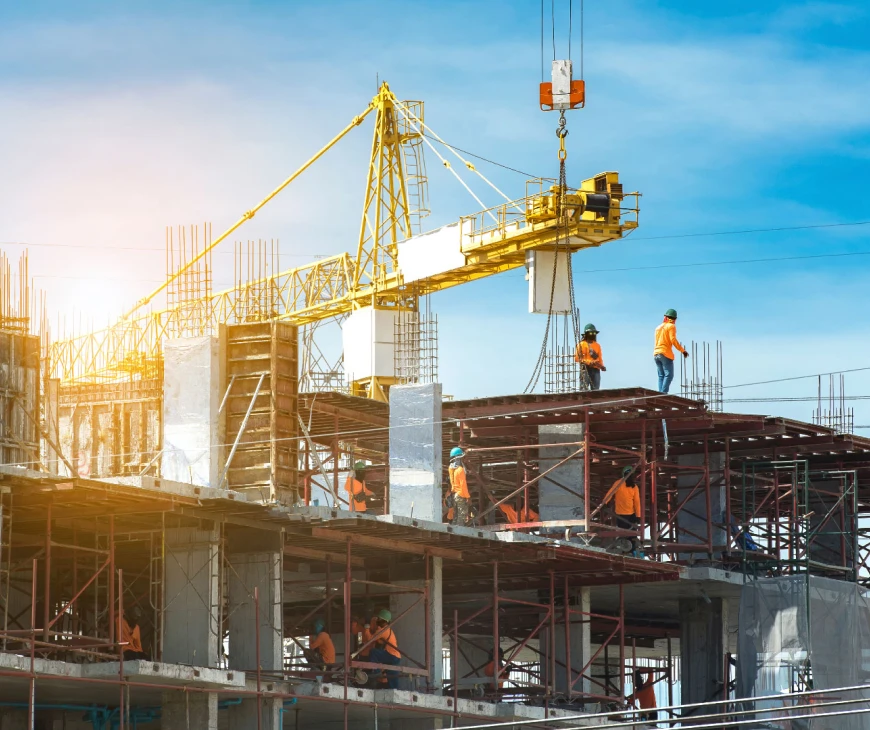 Workers in hi-vis on a concrete building site under a tower crane